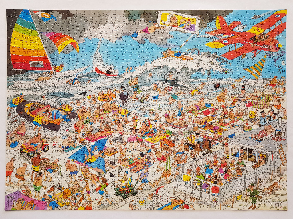 A crowded beach cartoon with numerous humorous scenarios, a red biplane, and a rainbow sailboat.