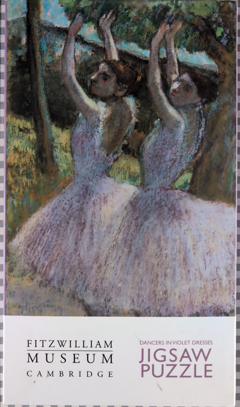 Two ballet dancers in voluminous violet tulle dresses dancing with arms raised against a wooded backdrop.