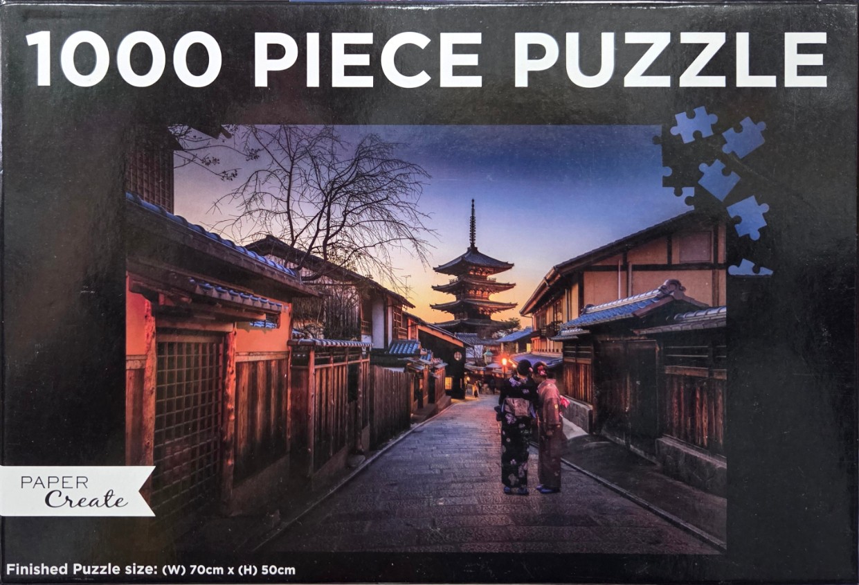 Two figures in traditional kimono walking down a narrow stone-paved street toward a distant pagoda at sunset.