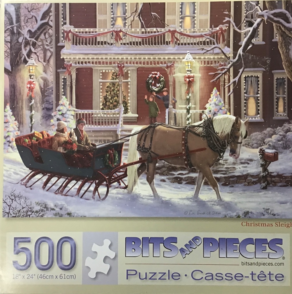 A horse-drawn sleigh carrying two people in front of a decorated Victorian home on a snowy Christmas evening.