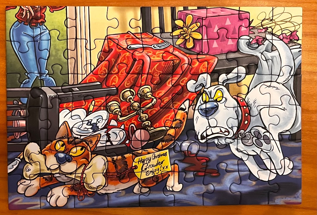 Cartoon cats and a dog in a messy Christmas scene with a red blanket and pink gift.