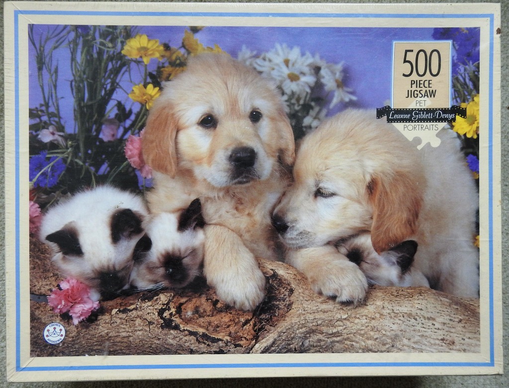 Two golden retriever puppies and two Siamese kittens resting together on a log in a flower garden