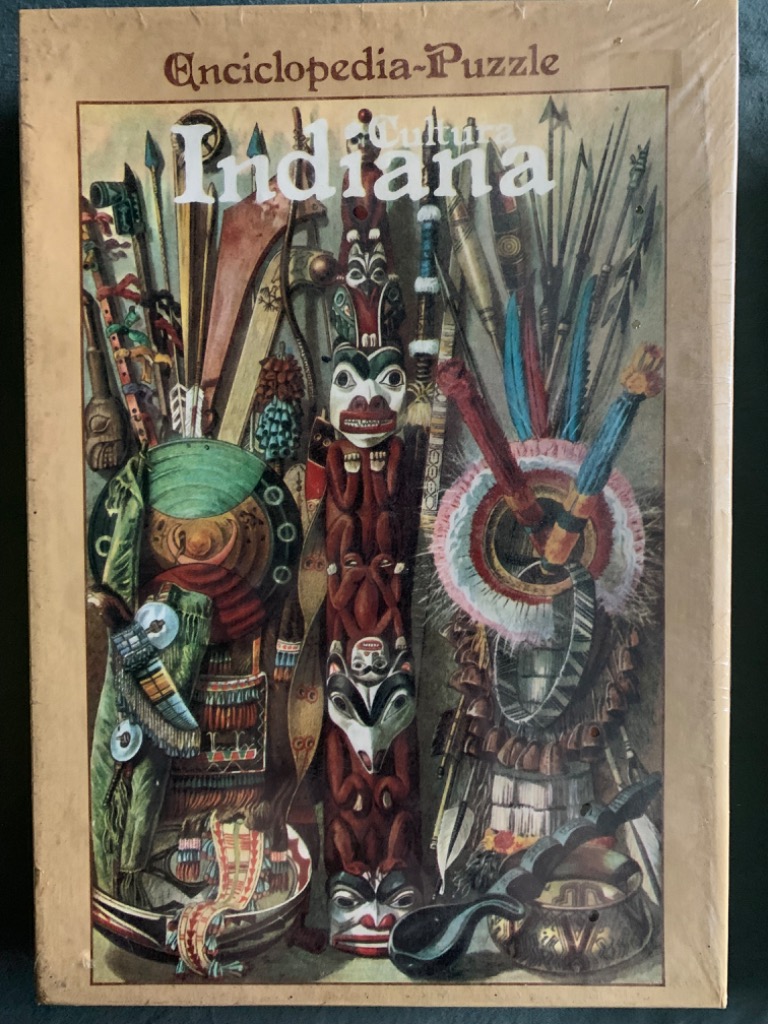 A collection of indigenous cultural artifacts including a central totem pole, feathered headdresses, and weaponry.