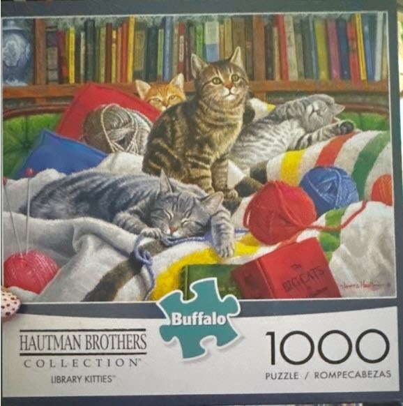 Several cats relaxing in a cozy library setting with yarn and books