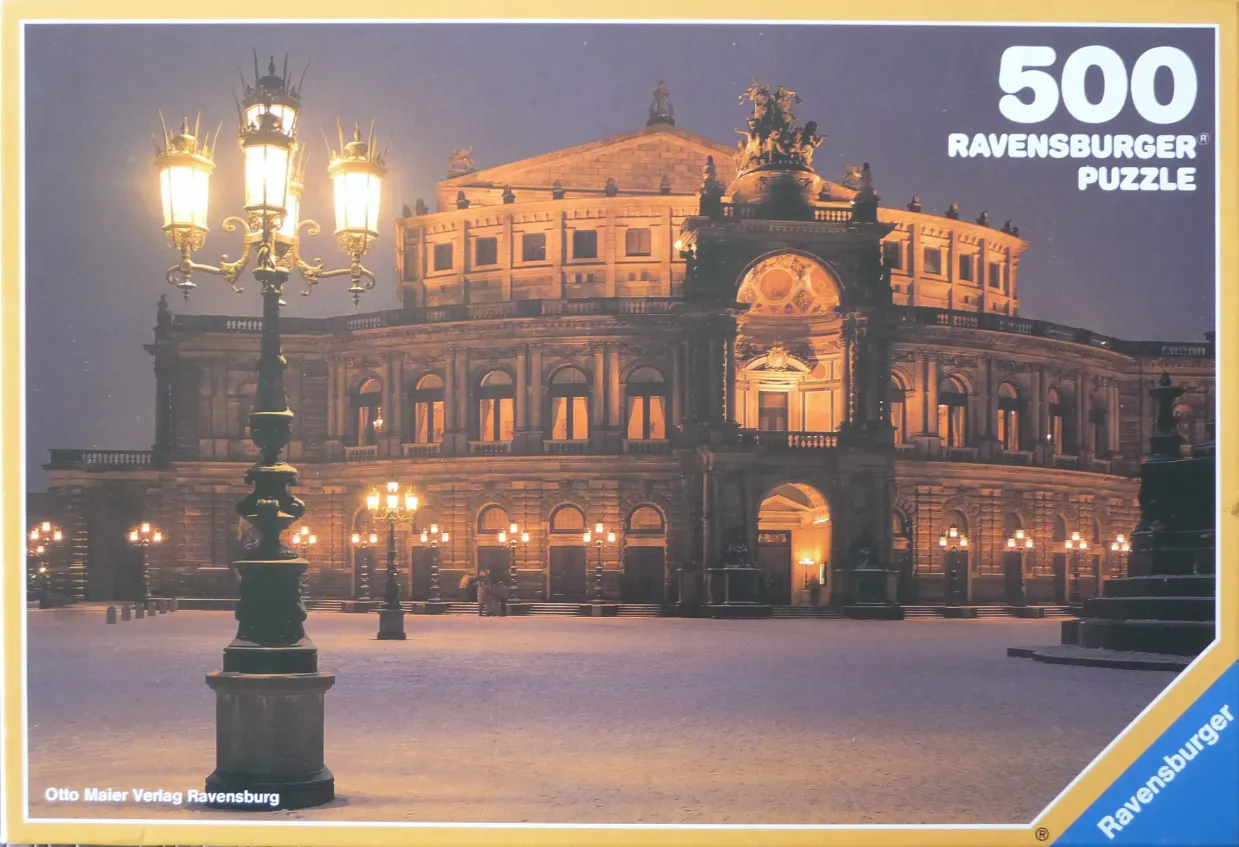 The Semperoper opera house in Dresden, Germany, illuminated at night with a large ornate lamppost in the foreground.
