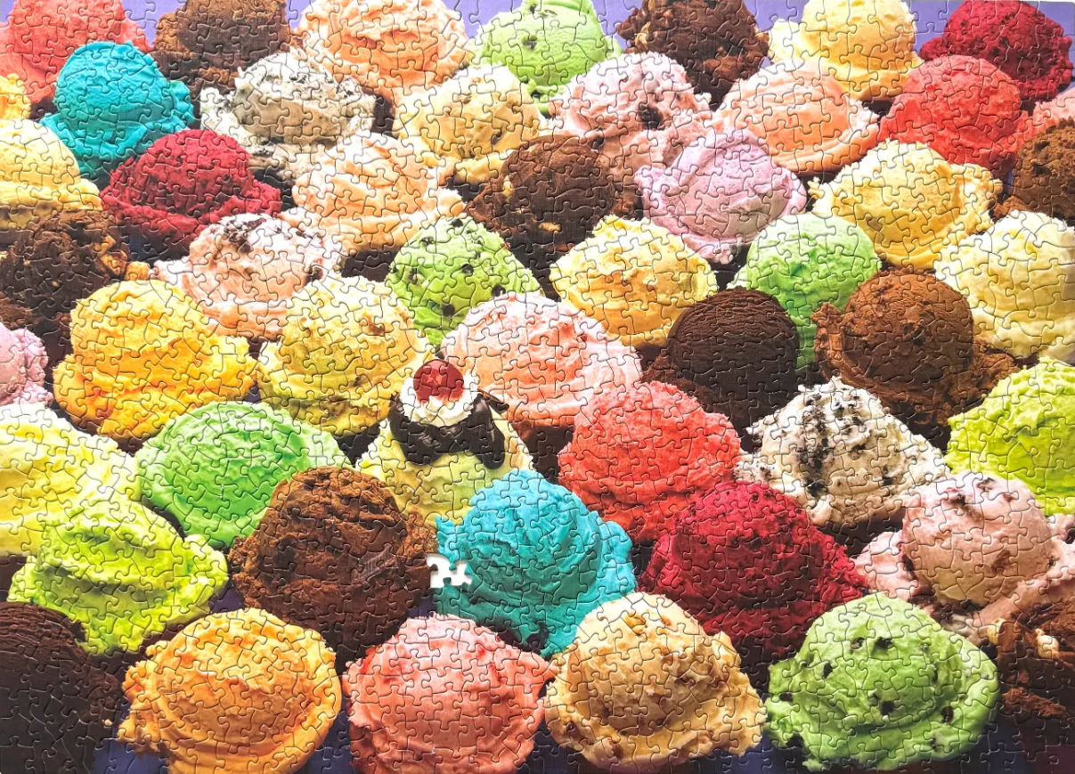 A top-down view of many scoops of colorful ice cream in various flavors packed together.