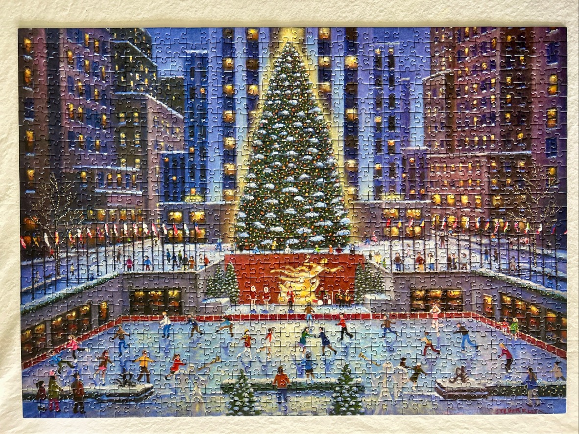 A bustling ice skating rink at Rockefeller Center during the holidays with a giant Christmas tree at the center.