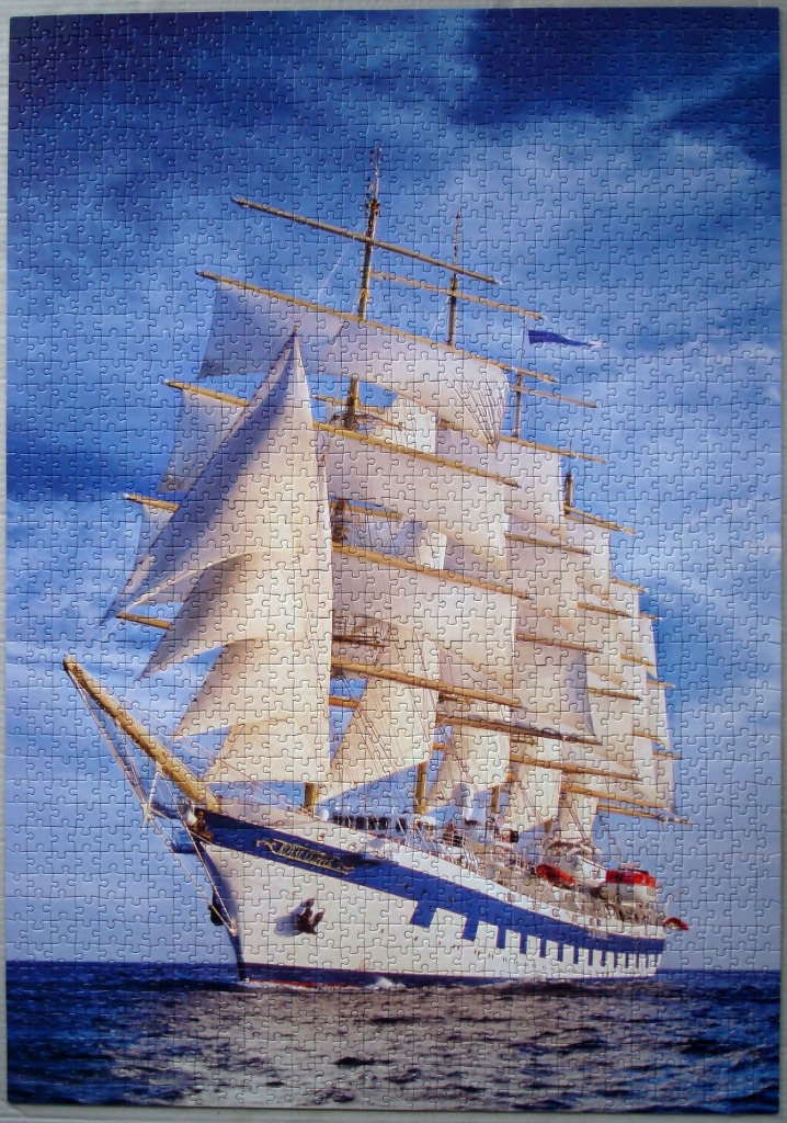 A majestic tall ship with full sails sailing across a deep blue ocean under a partly cloudy sky.