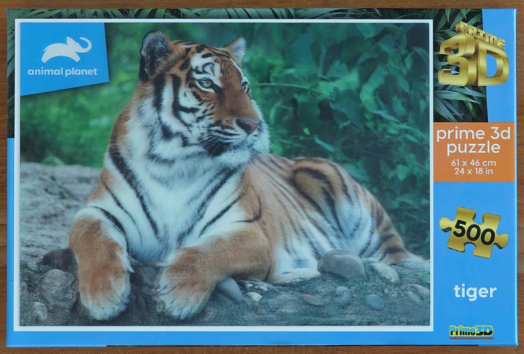 A majestic tiger resting on a rocky ledge against a backdrop of lush green foliage.