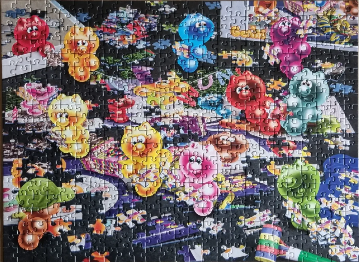 A whimsical collage of numerous colorful cartoon gummy bear-like creatures against a dark background.
