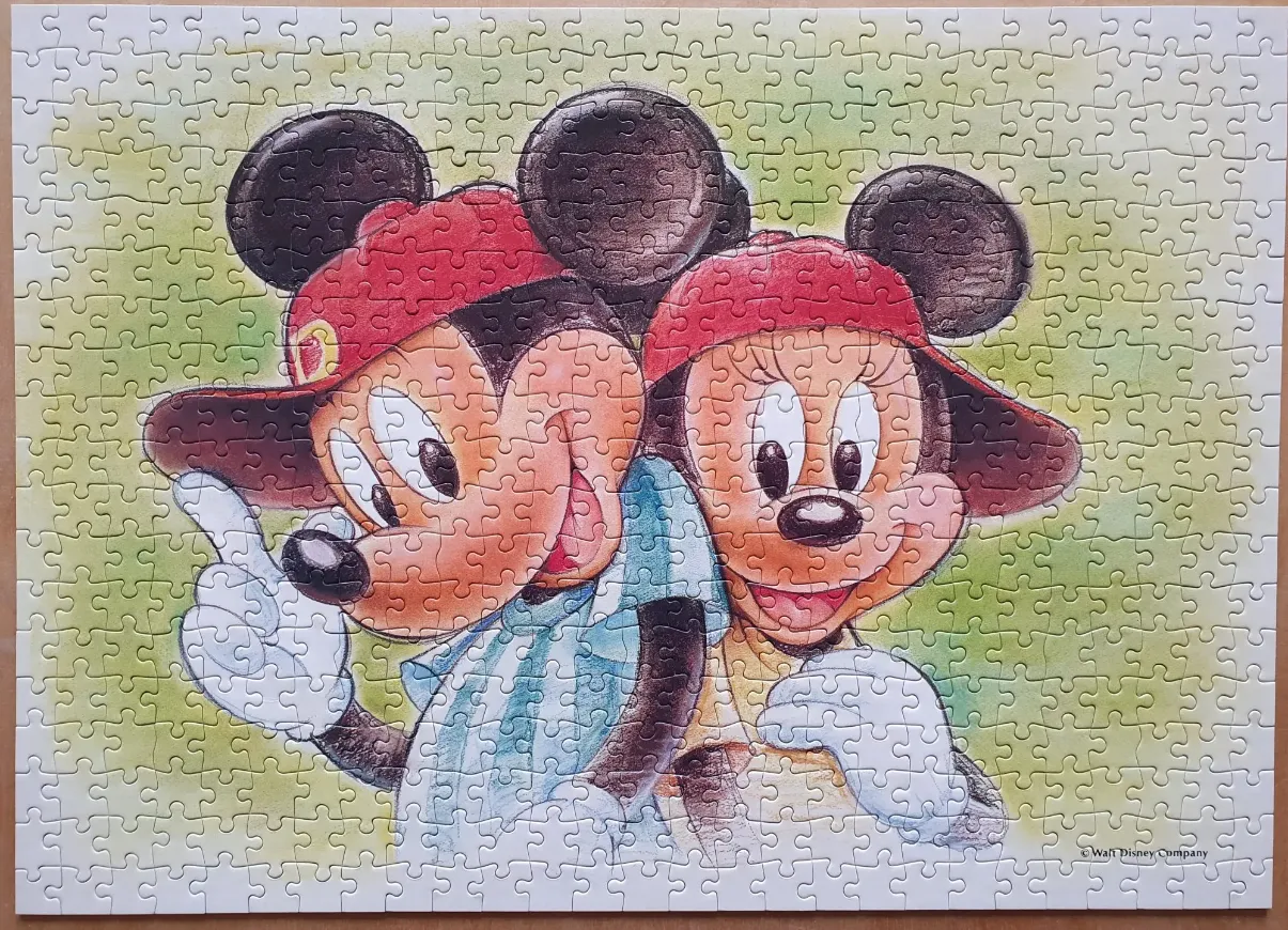 Mickey and Minnie Mouse wearing red baseball caps and casual clothing against a green wash background.