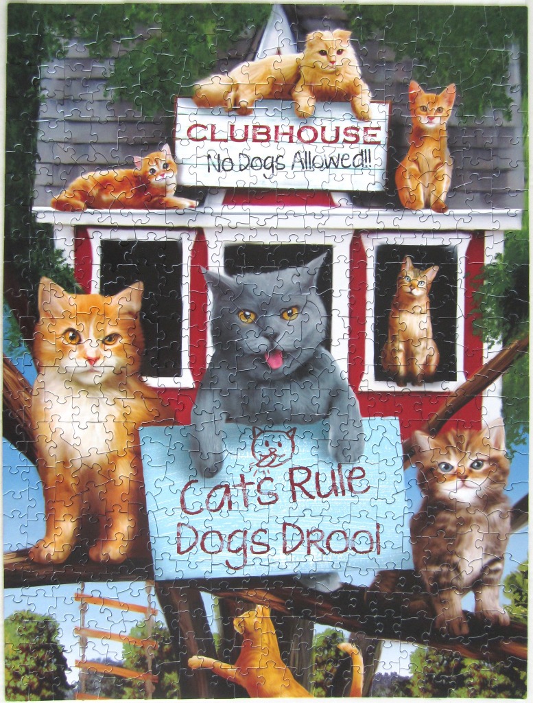 Seven cats gathered at a red clubhouse with a sign reading Clubhouse No Dogs Allowed and a smaller sign Cats Rule Dogs Drool