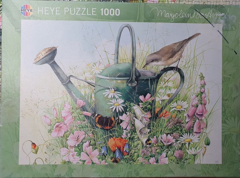 A green metal watering can nestled in a lush garden with flowers, a small bird, and a butterfly.