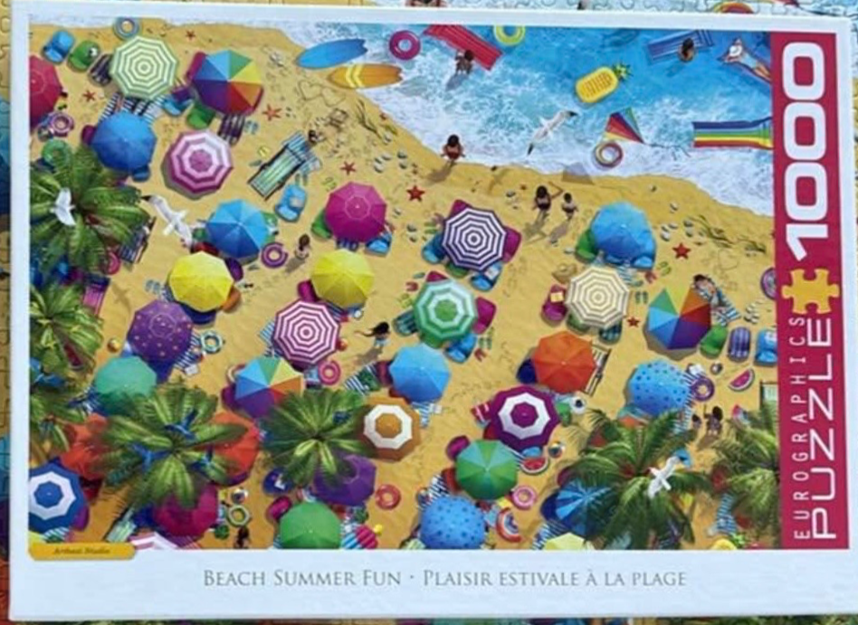 Aerial view of a busy tropical beach with numerous colorful umbrellas, people, and summer accessories.