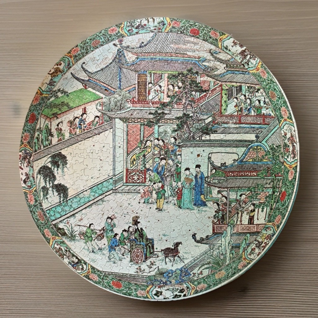 A circular artwork depicting a classical Chinese courtyard scene with figures in traditional clothing.
