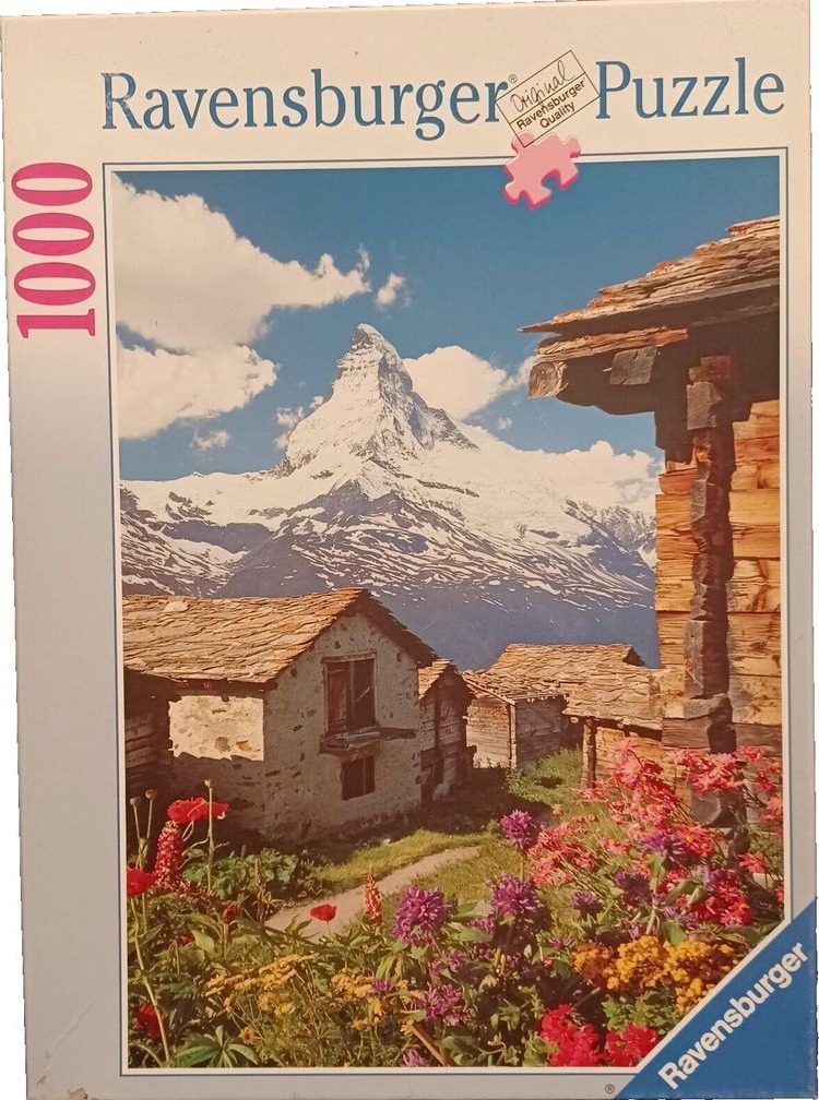 A photograph of traditional stone cottages in front of the Matterhorn mountain in Switzerland with flowers in foreground.