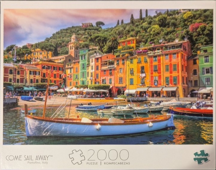 A picturesque harbor in Portofino, Italy with colorful buildings, fishing boats, and a lush green hillside.