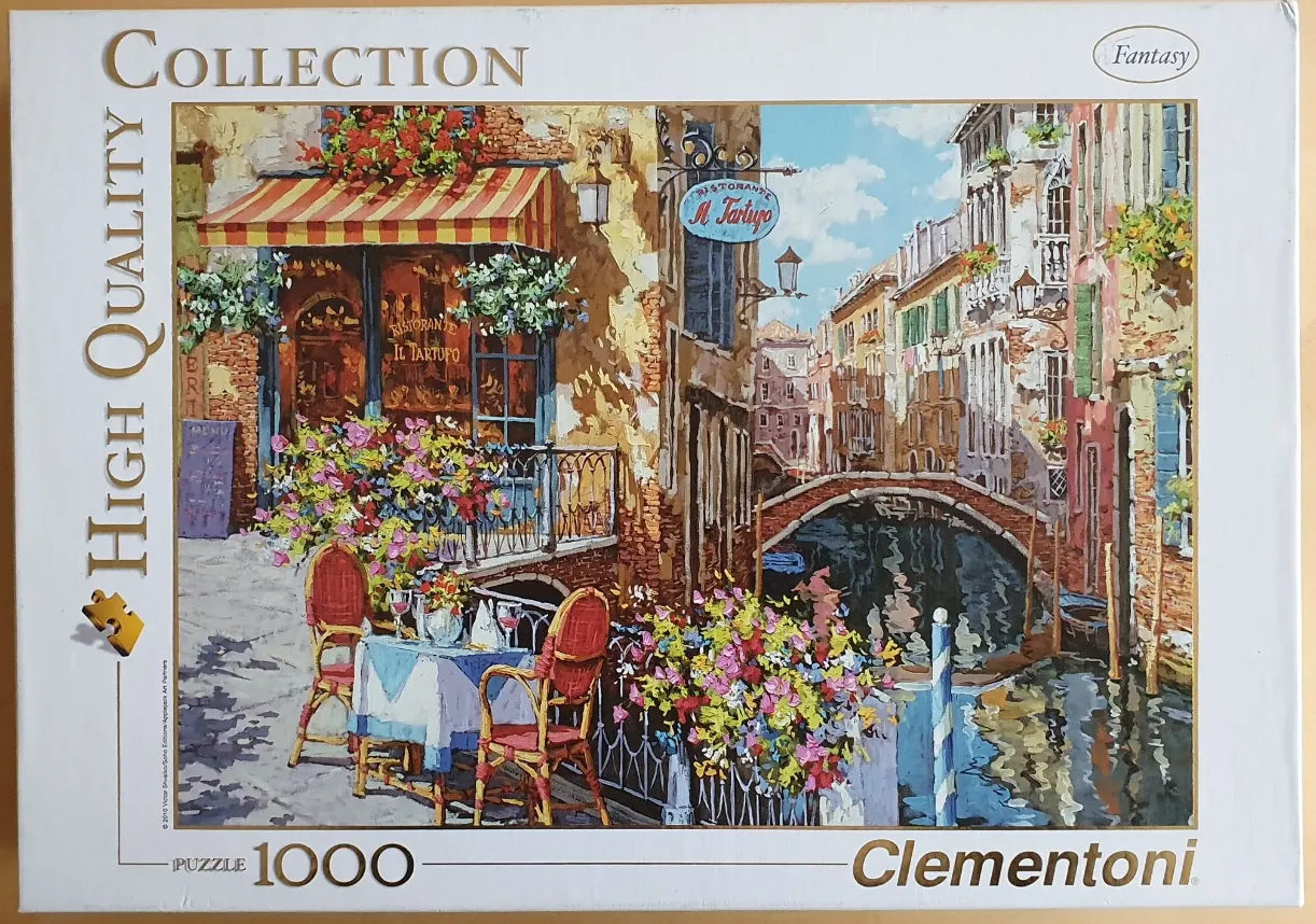 Painting of a cozy Venetian canal-side restaurant with a table, chairs, and flowers.