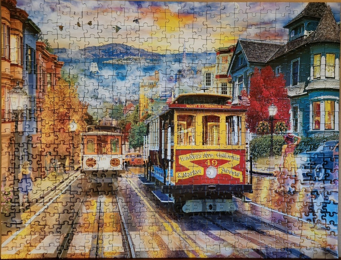 A San Francisco street scene with iconic cable cars traveling down a hilly road at sunset.