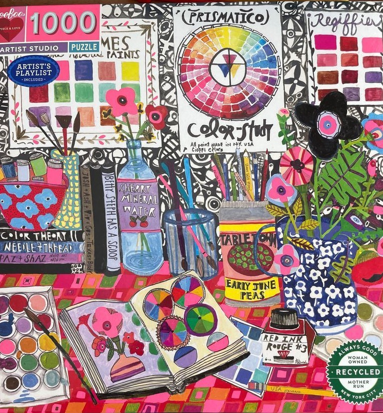 Illustrated artist's desk filled with sketchbooks, paint supplies, and floral arrangements in a vibrant, patterned style.