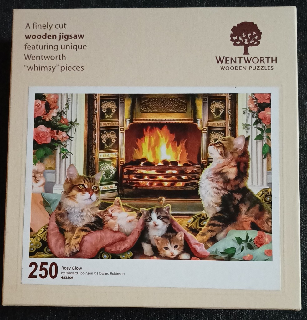 Five cats of various ages and colors resting together in front of a warm fireplace.