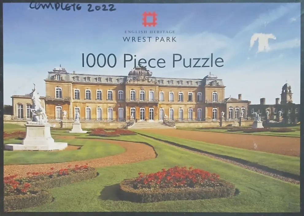 A stately stone mansion in a grand garden with formal lawns, flowerbeds, and statues under a blue sky.
