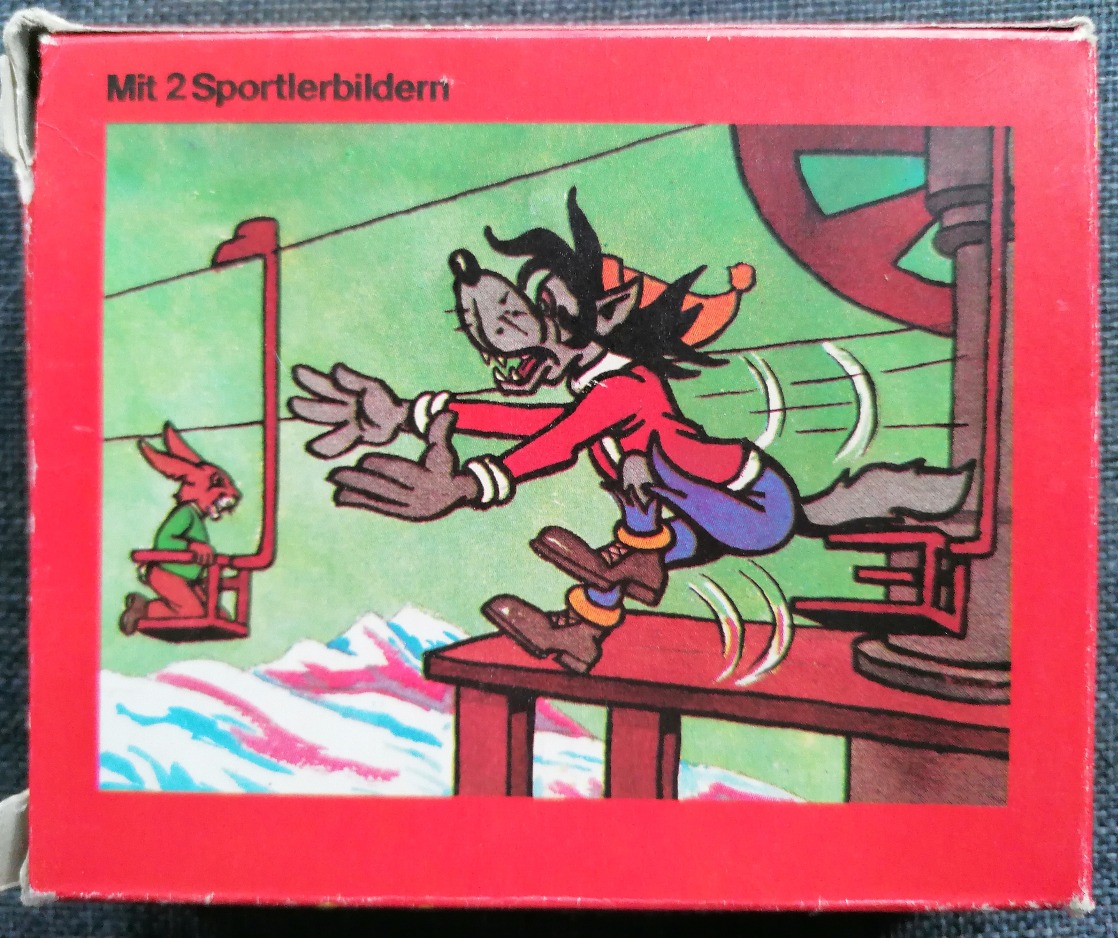 A cartoon wolf jumping from a chairlift toward a red rabbit, set against a mountainous background.