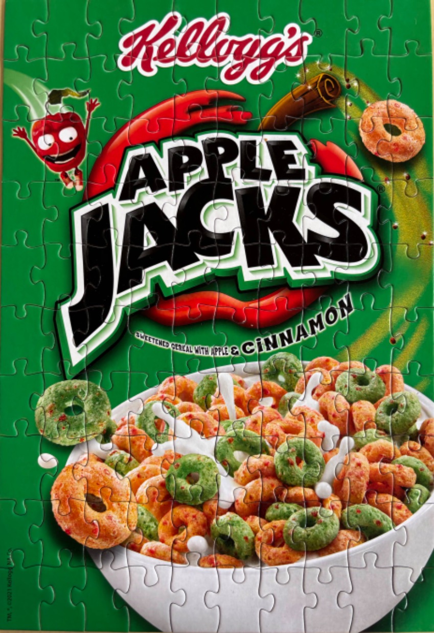 A box front of Apple Jacks cereal with a bowl of cereal and milk against a bright green background.