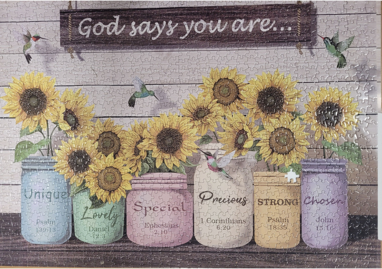 A collection of sunflowers in pastel mason jars with inspirational text against a wooden background.