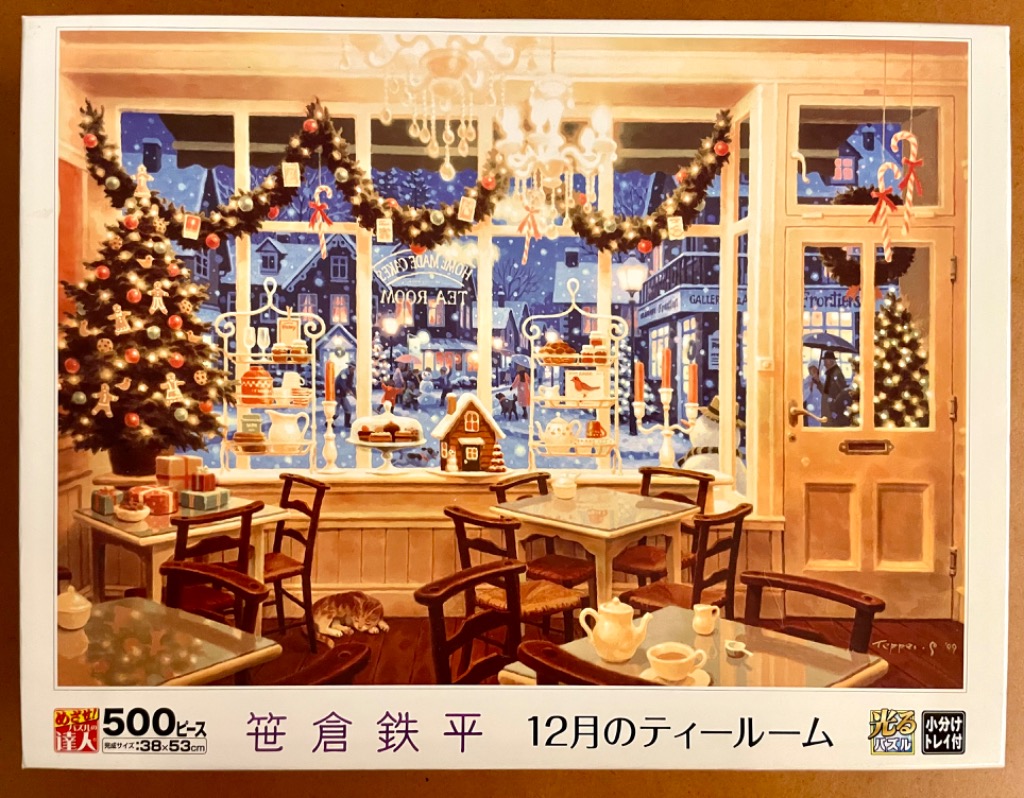 Cozy, candlelit tea room decorated for Christmas, with a view of a snowy village street through large windows.