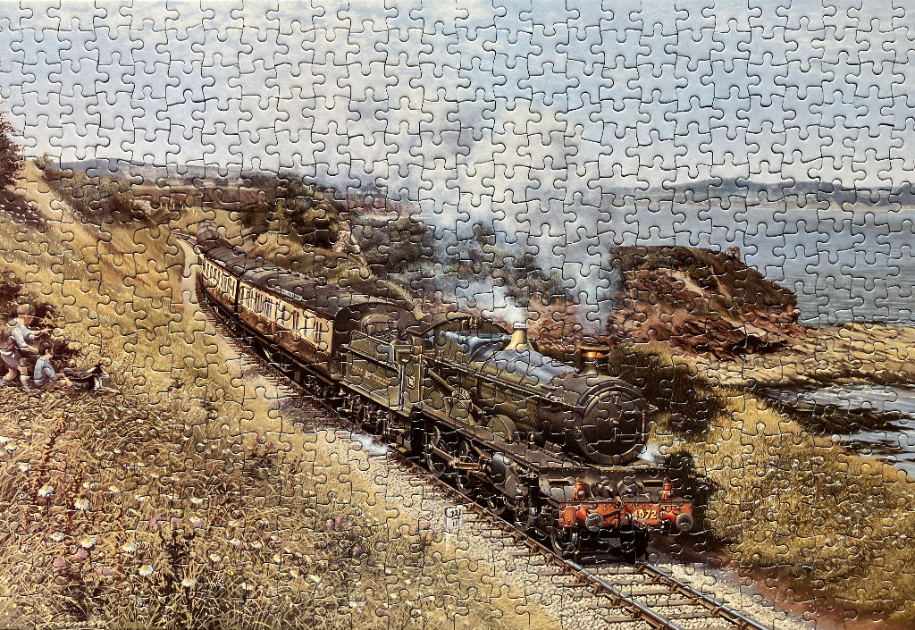 A vintage steam locomotive pulling a train along a coastal track past grassy hills and onlookers.