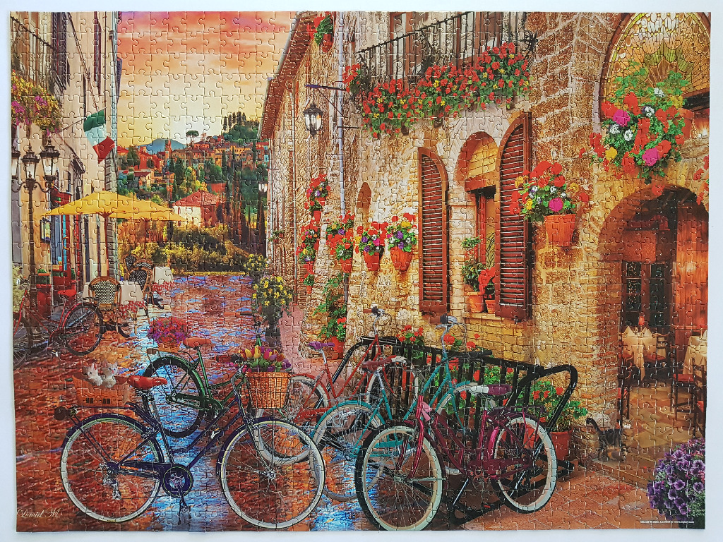 A charming Italian street scene with bicycles, flowers, and rustic stone buildings at sunset.