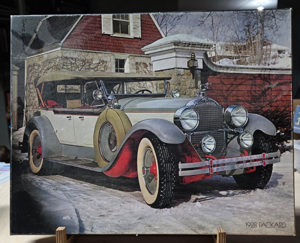 A vintage 1928 Packard automobile parked in front of a house on a snowy day.