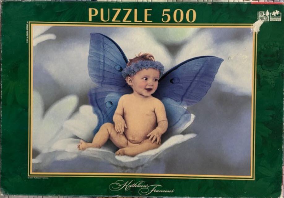 A smiling infant with blue fairy wings sitting on a large white flower petal.
