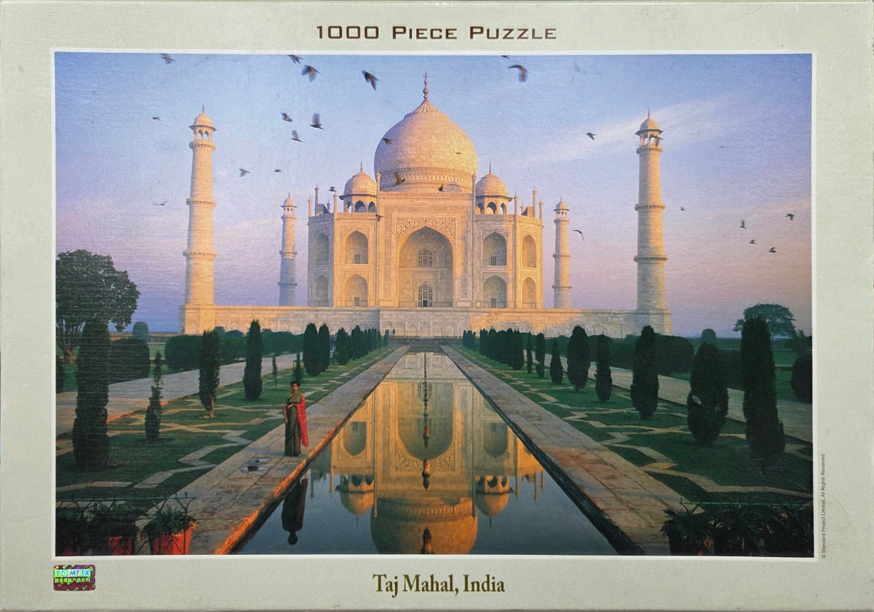 A photograph of the Taj Mahal at sunset with a reflecting pool and a woman in a sari in the foreground.