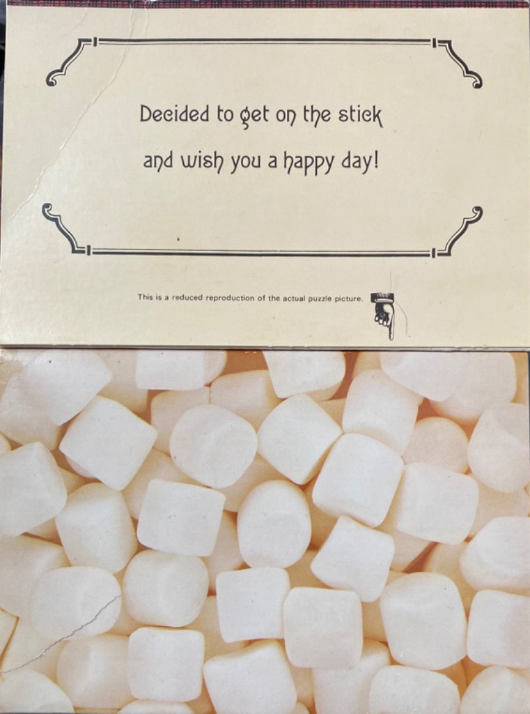 Text on a cream-colored plaque above a jumbled heap of white, square-shaped marshmallows.