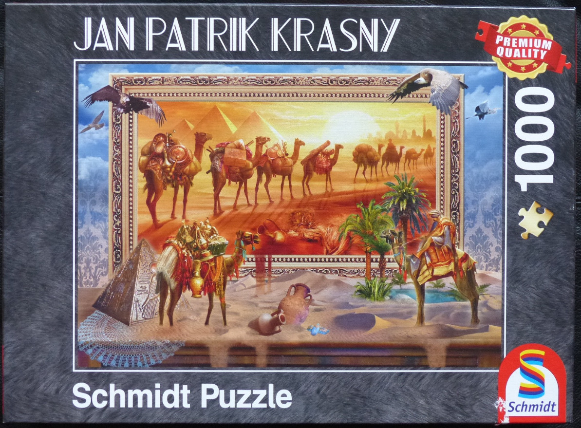 An ornate, gold-framed picture of an Egyptian desert scene with camels resting on a table alongside ancient artifacts.