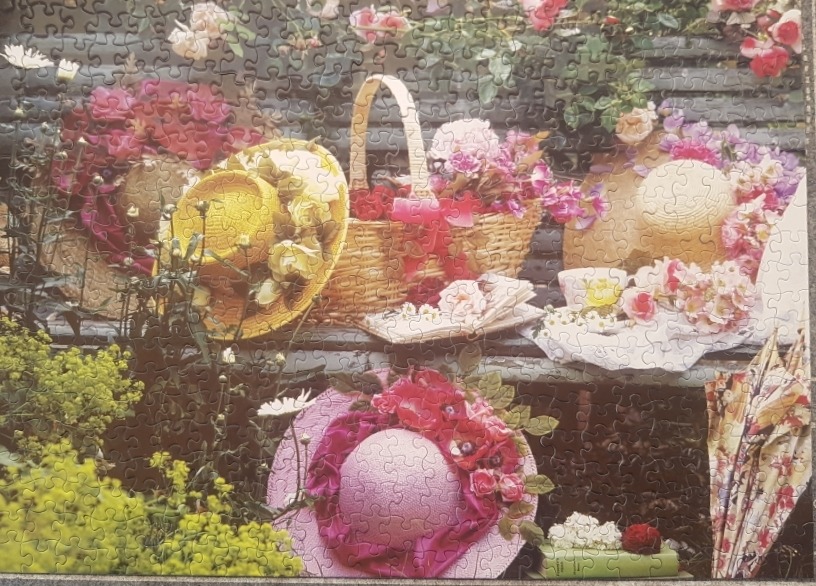 A charming garden still life featuring straw hats, a basket, and flowers arranged on a rustic wooden bench.