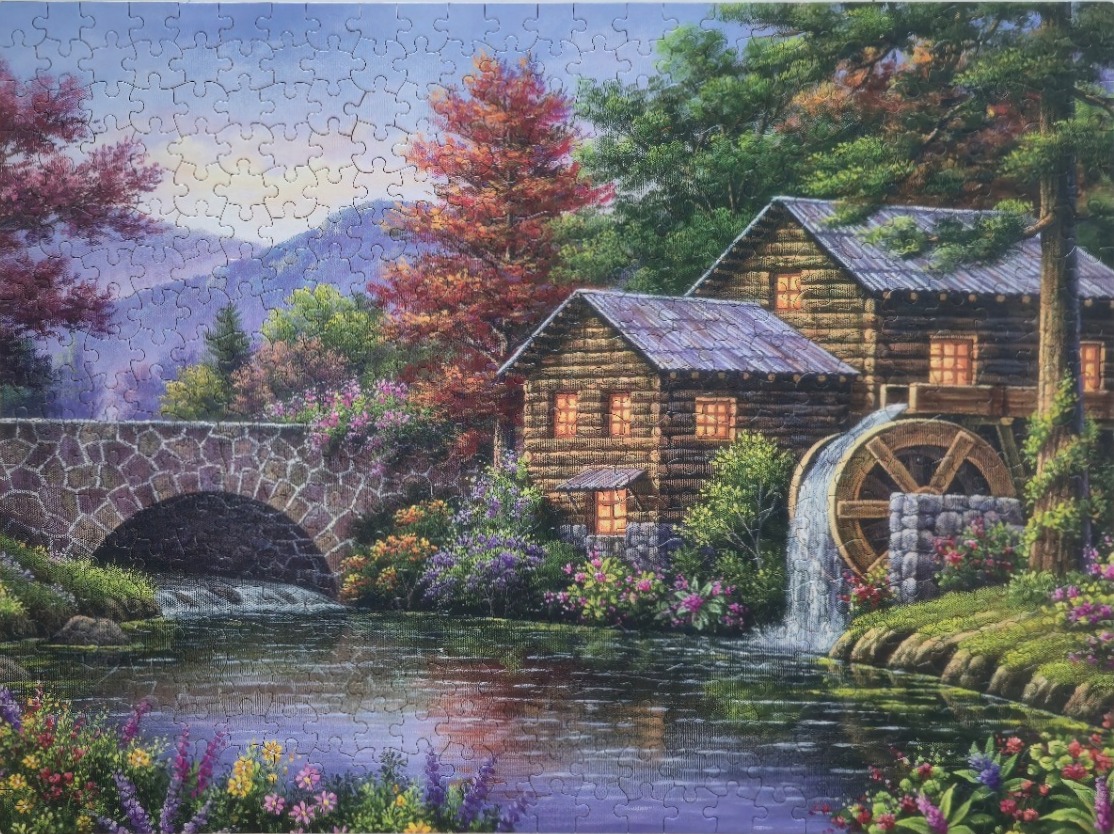 An illustration of a rustic log watermill nestled beside a stone bridge and a stream during autumn.