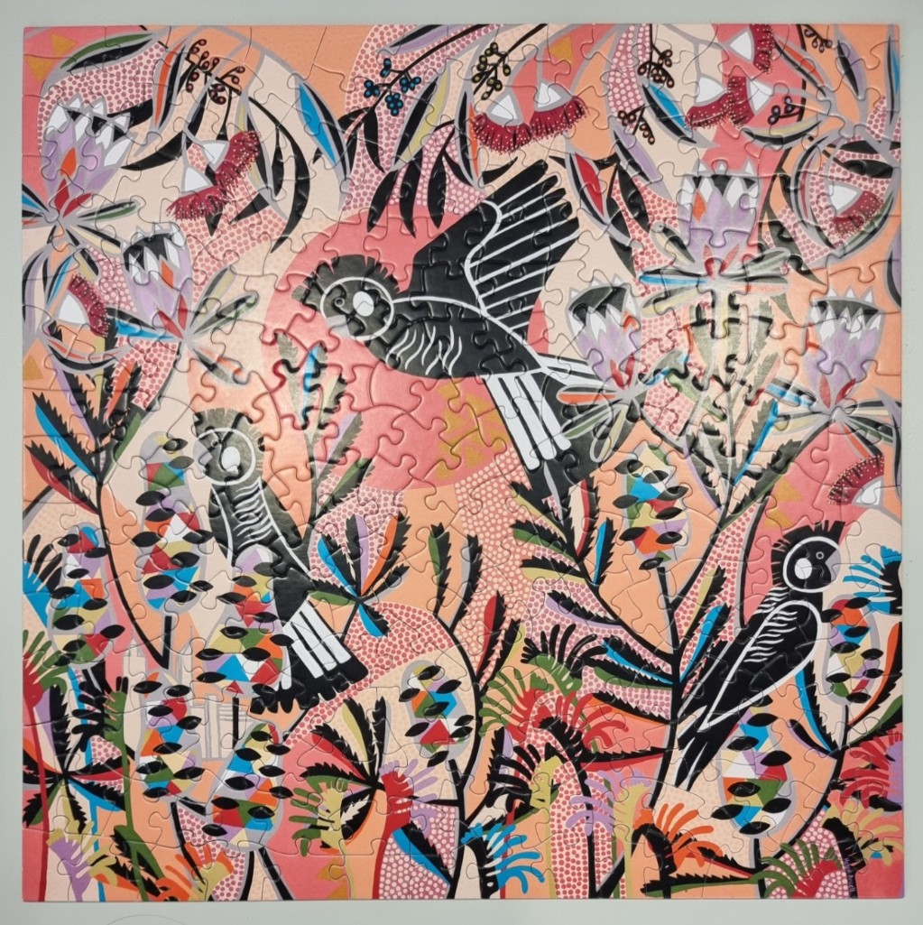 Stylized illustration of black cockatoos amidst Australian native flora in shades of pink, orange, and teal.