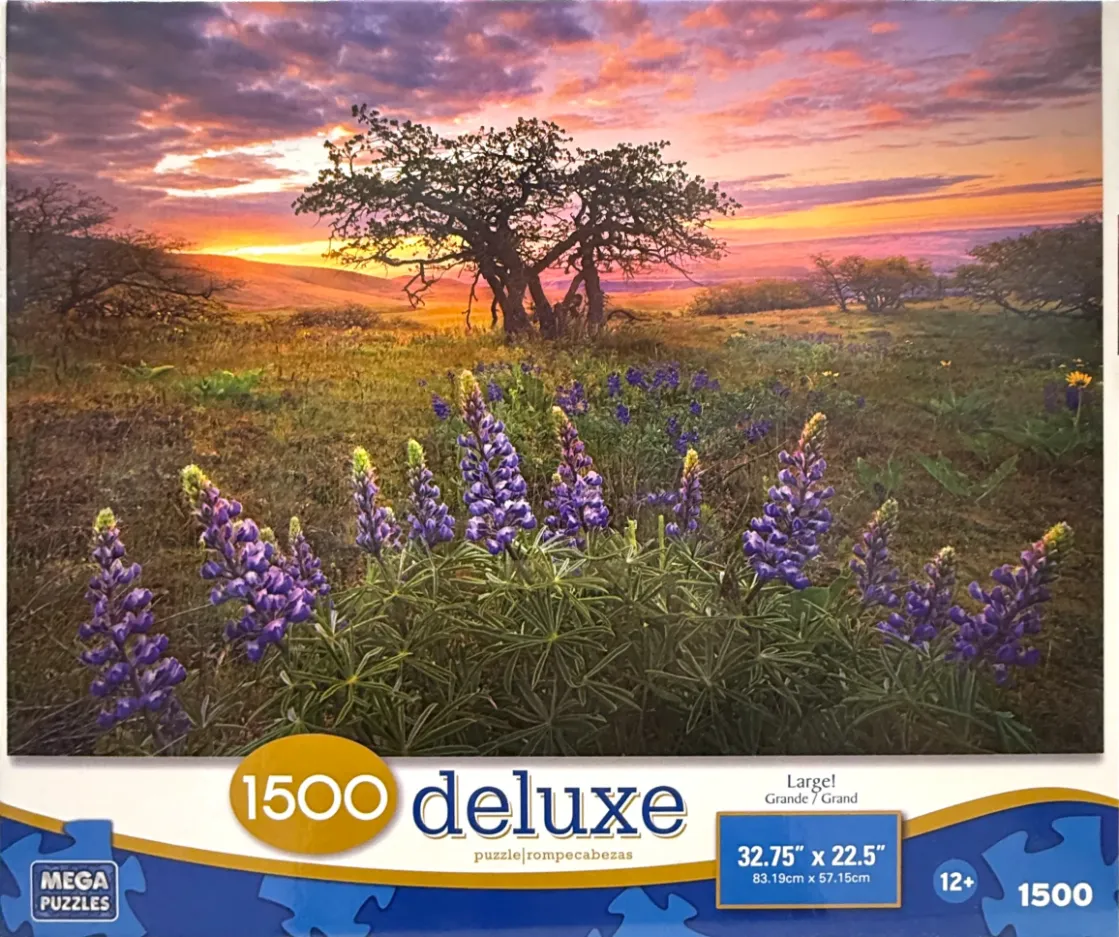A scenic photograph of a meadow filled with purple lupine flowers under a vibrant sunset with a single tree in the distance.