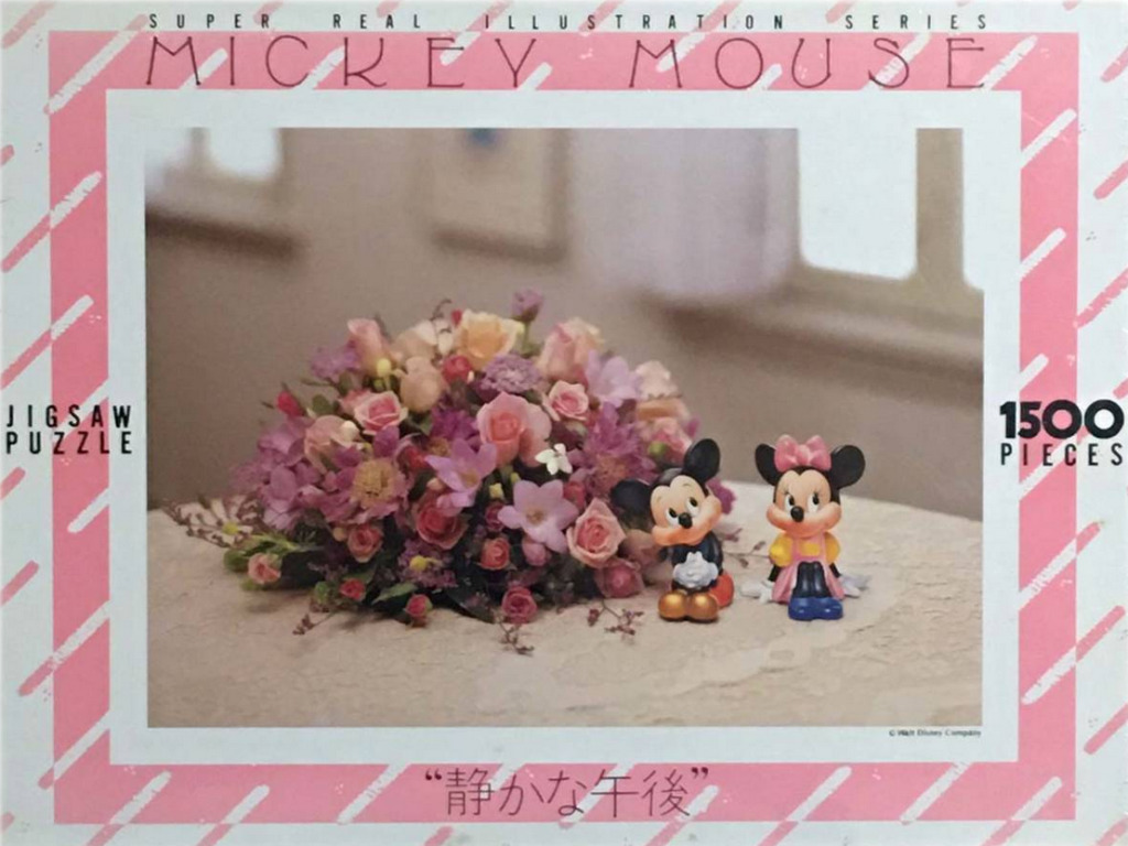 Mickey and Minnie Mouse figurines standing beside a large, lush floral arrangement on a textured surface.
