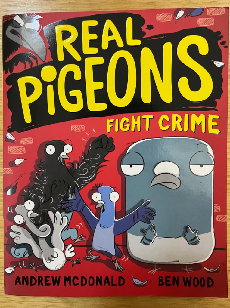 Cartoon illustration of four pigeon characters standing against a red brick-textured background.