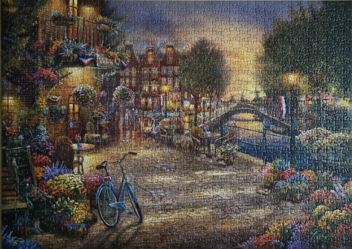A scenic evening view of a cobblestone canal-side café in Europe with a blue bicycle in the foreground.