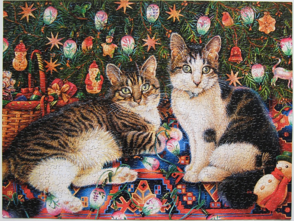 Two tabby and white cats sitting in front of a decorated Christmas tree.