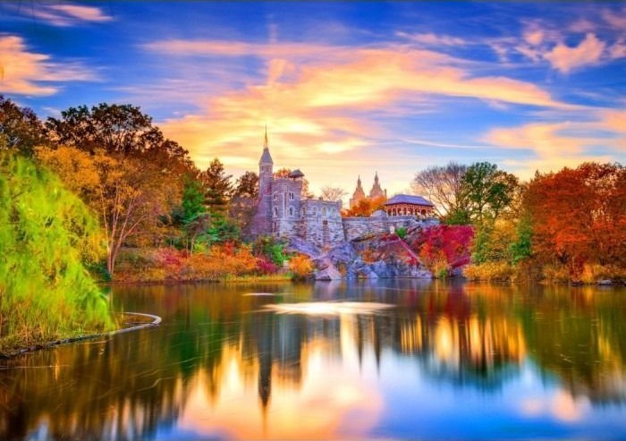 A stone castle reflected in a still pond at sunset surrounded by autumn trees.
