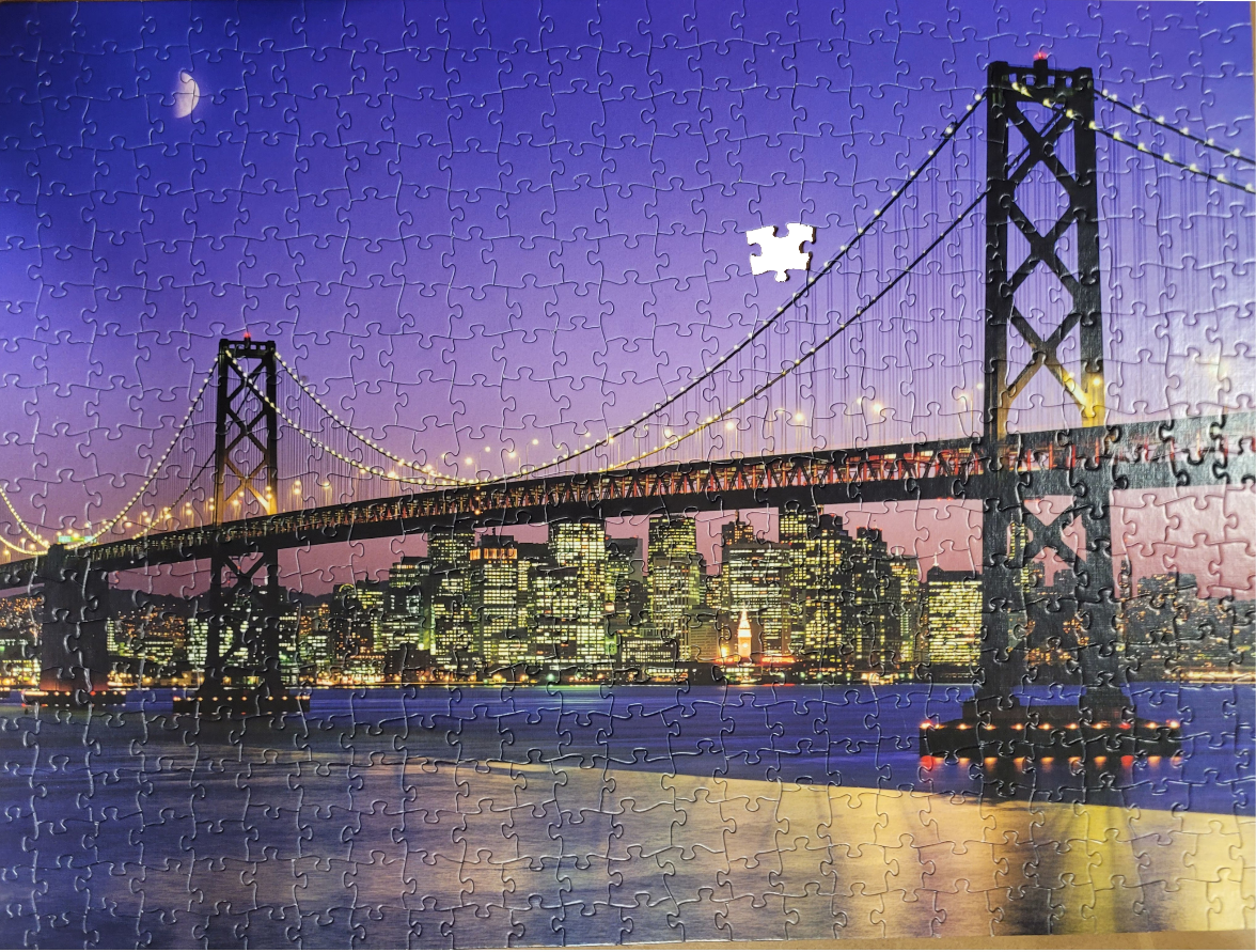 The Bay Bridge at twilight with the illuminated San Francisco skyline in the background.