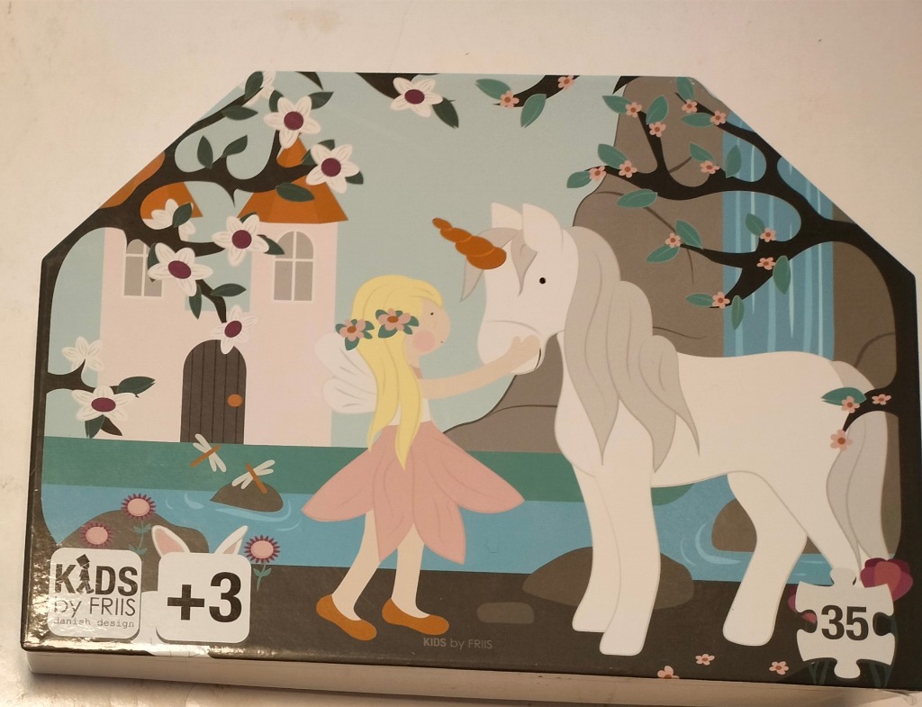 Illustrated scene of a fairy in a pink dress standing with a white unicorn in front of a castle and a waterfall.