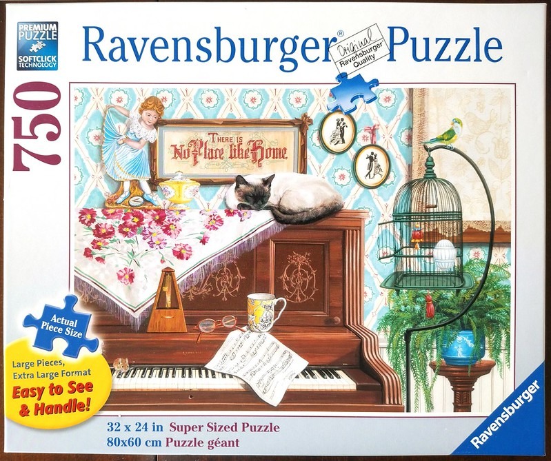 A cozy vintage interior scene featuring a cat sleeping on a piano in front of a blue floral wallpaper.