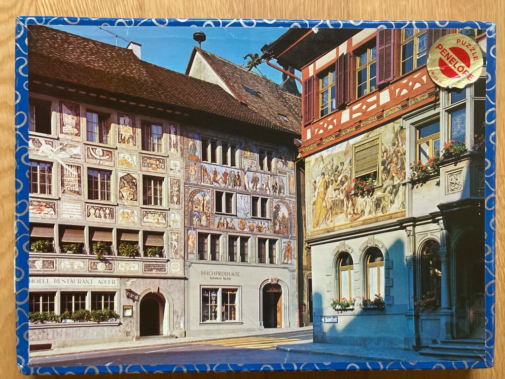 A view of traditional Swiss buildings featuring ornate fresco paintings on their facades.